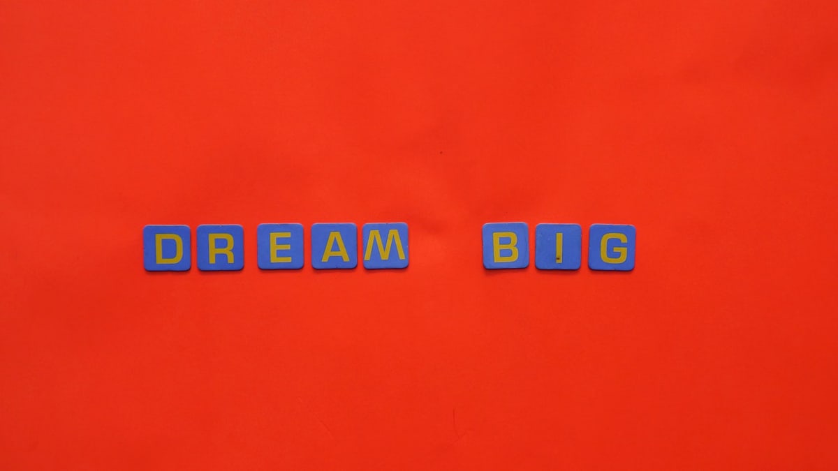 Blue tiles forming the 'Dream Big' quote against a striking red background.
